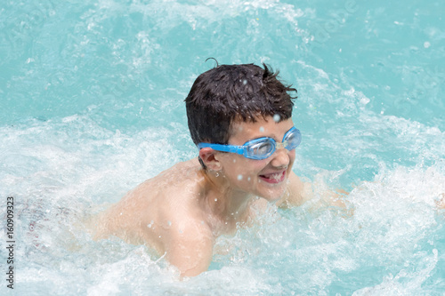 Boy laughing and swimming, creating lots of waves, splashes and bubbles