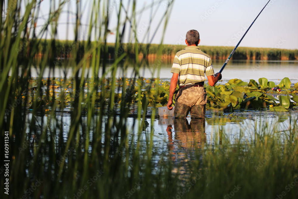 Man fishing with rod while standing in water Stock Photo