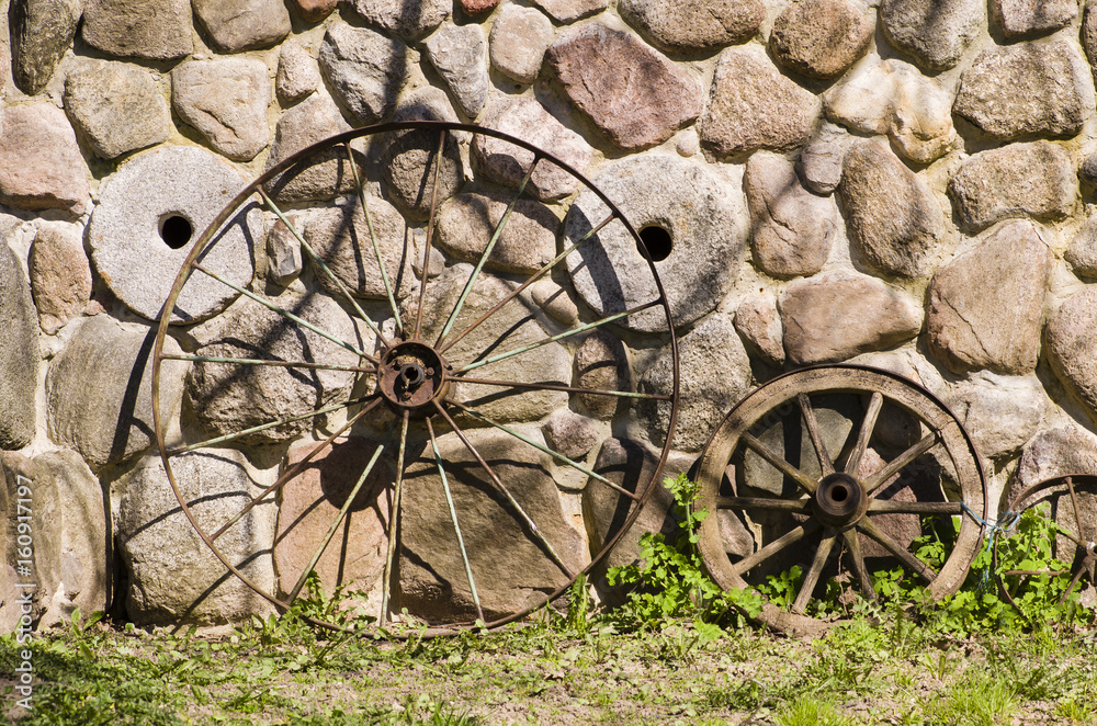 The wheel of a cart near the stone wall