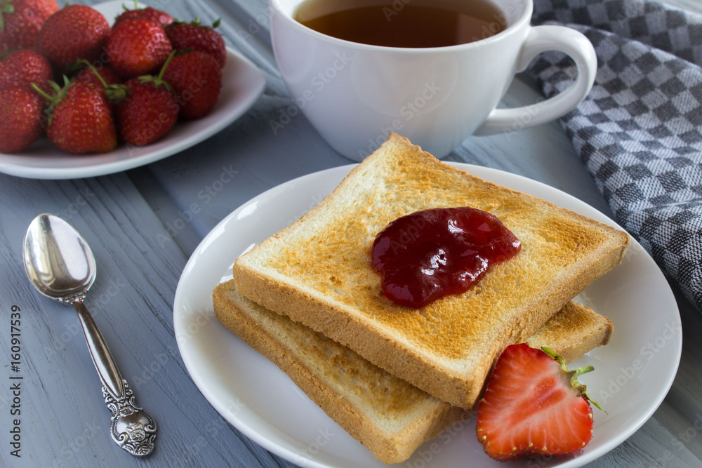 Bread toast with strawberry jam and tea on the grey background Bread toast with strawberry jam and tea on the grey background