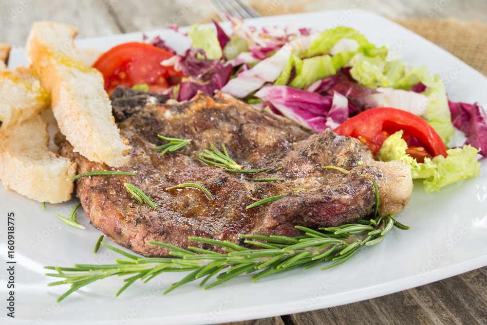 Braciola di maiale arrosto con contorno di insalata fresca e crostini 