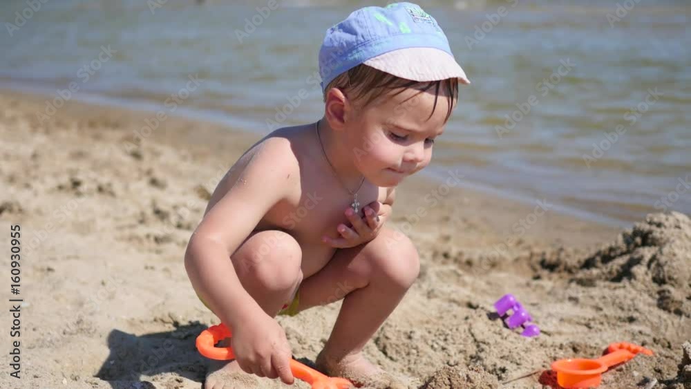 A child plays with sand and toys on the beach on a sunny hot day A child plays with sand and toys on the beach on a sunny hot day