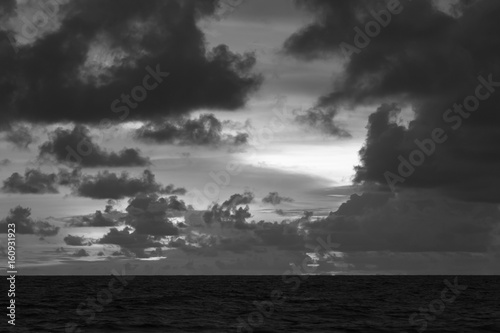 Dark pink sunset in clouds over the sea - black and white