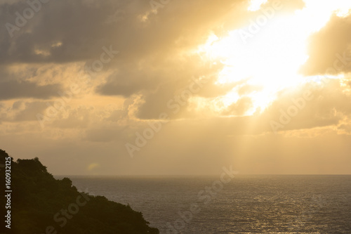 The sun in the clouds above the sea and the island