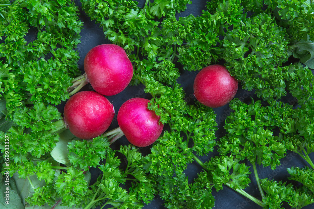 Fresh aromatic juicy ripe radish vegetables and juicy green parsley dill pepper bay leaf layout pattern on a dark background. Concept of healthy eating and vegetarianism.Space of copying.top view flat