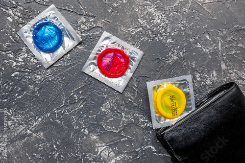 male contraception for safe sex with condoms in wallet on dark background top view