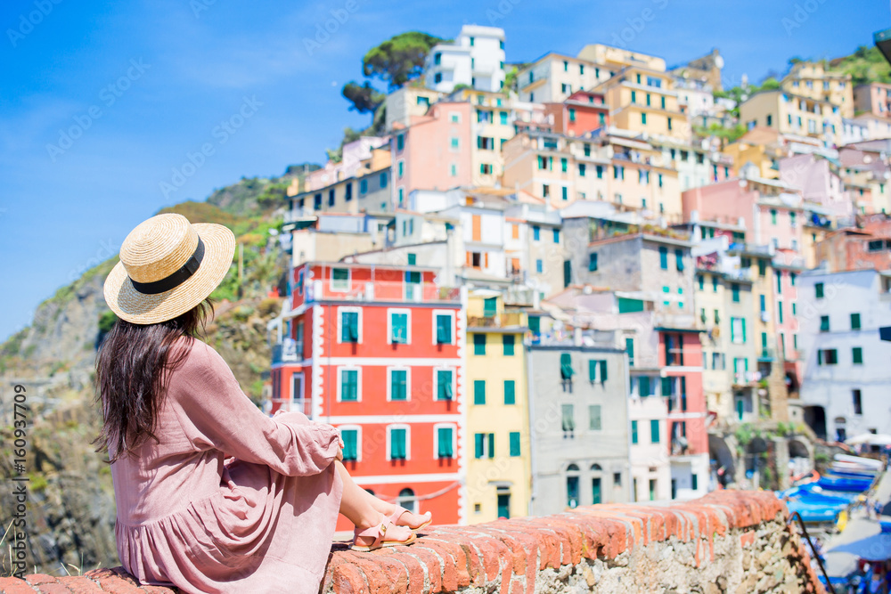 Young woman with great view at old village Riomaggiore, Cinque Terre, Liguria, Italy. European italian vacation.