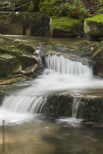 Beautiful waterfall with moss on the stones in the woods.