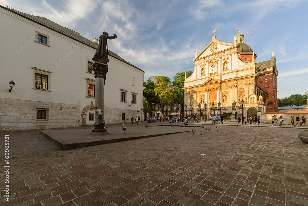 Square, monument and church in Krakow, Poland in the evening