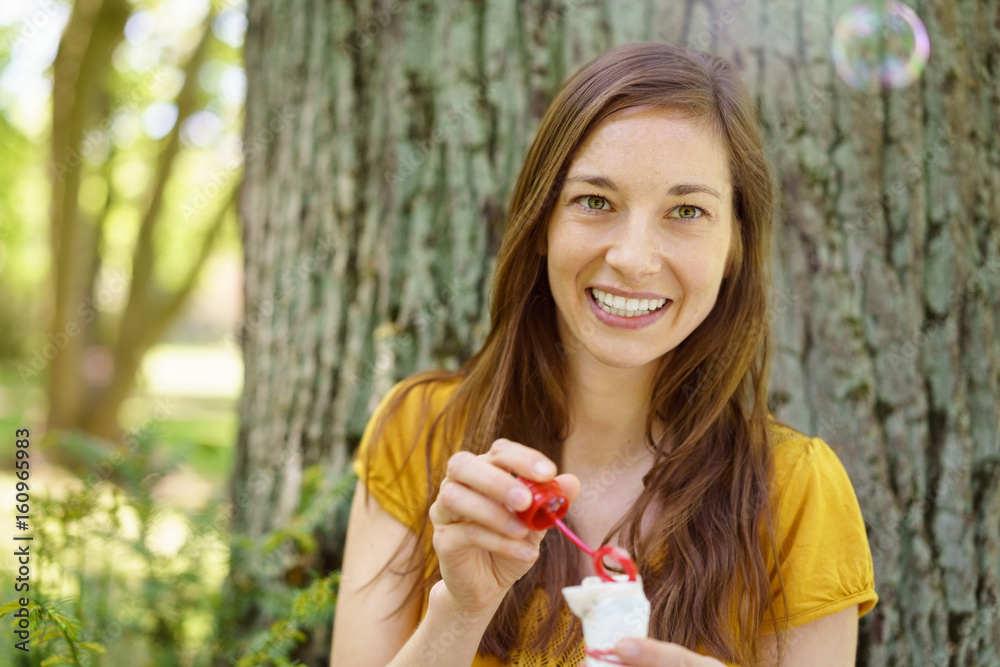 Cheerful girl with bubble blower in park