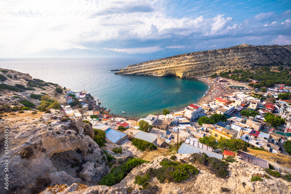 Panorama of Matala beach with caves on the rocks that were used as a roman cemetery and at the decade of 70's were living hippies from all over the world, Crete, Greece