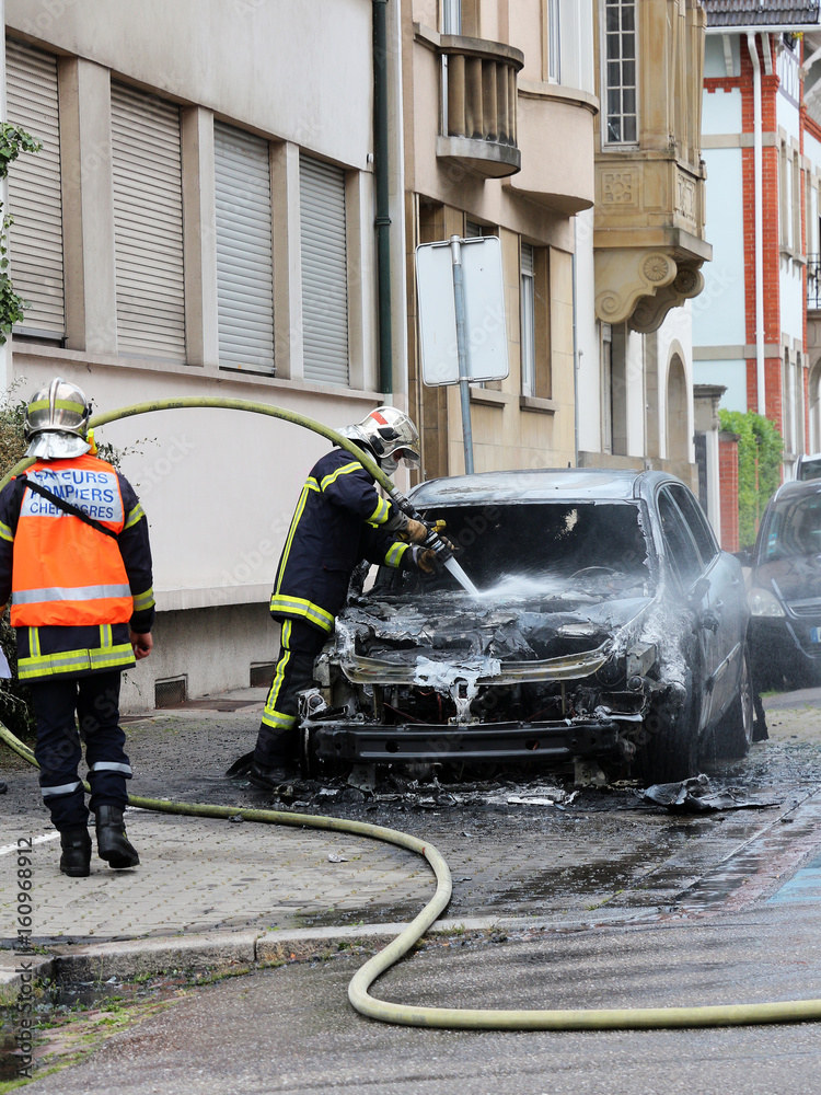 Obraz premium Burnt out car and firemen