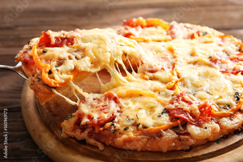 Close up view of pizza slice lifted from wooden plate