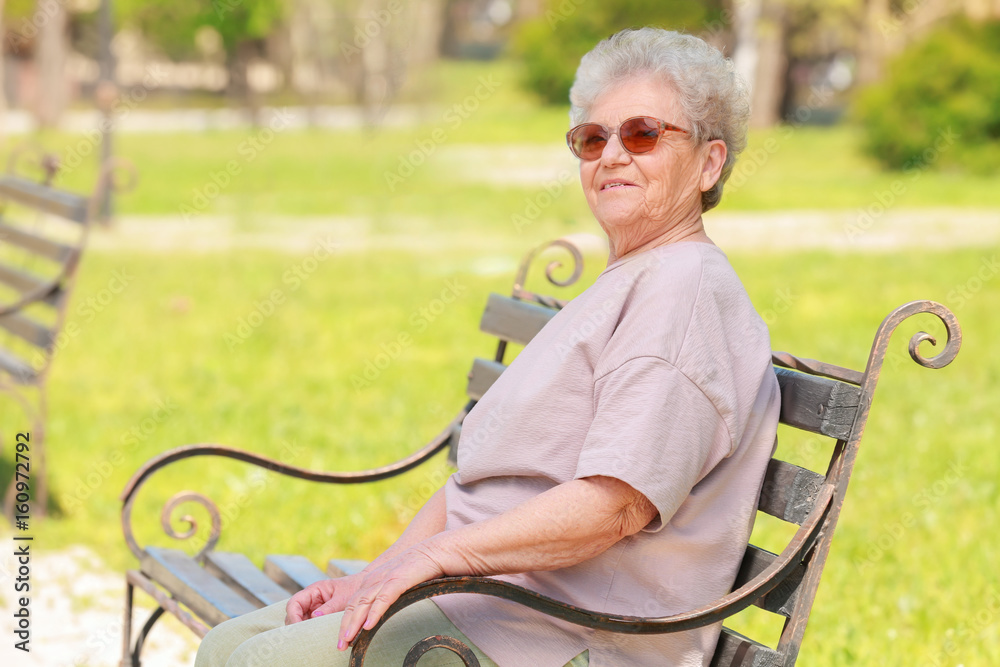 Elderly woman sitting on bench in park Elderly woman sitting on bench in park