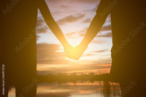 Couple holding hands a watching a beautiful sunset