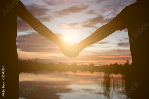 Couple holding hands a watching a beautiful sunset