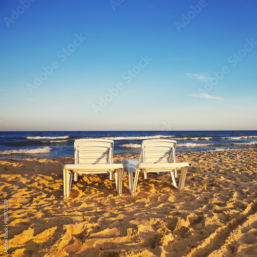 Two deckchairs on the sandy beach