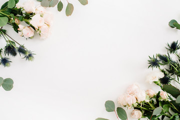 Border frame made of beige rose flowers, eringium flower, eucalyptus branches on white background. Flat lay, top view. Floral background