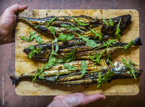 grilled mackerel on the wooden board with hands