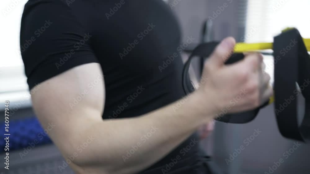 Close up of a man wearing a black sportswear doing one arm push ups with gymnastic rings in a gym. Concept of staying fit and healthy. Real time tilt down tilt up close up shot Close up of a man wearing a black sportswear doing one arm push ups with gymnastic rings in a gym. Concept of staying fit and healthy. Real time tilt down tilt up close up shot