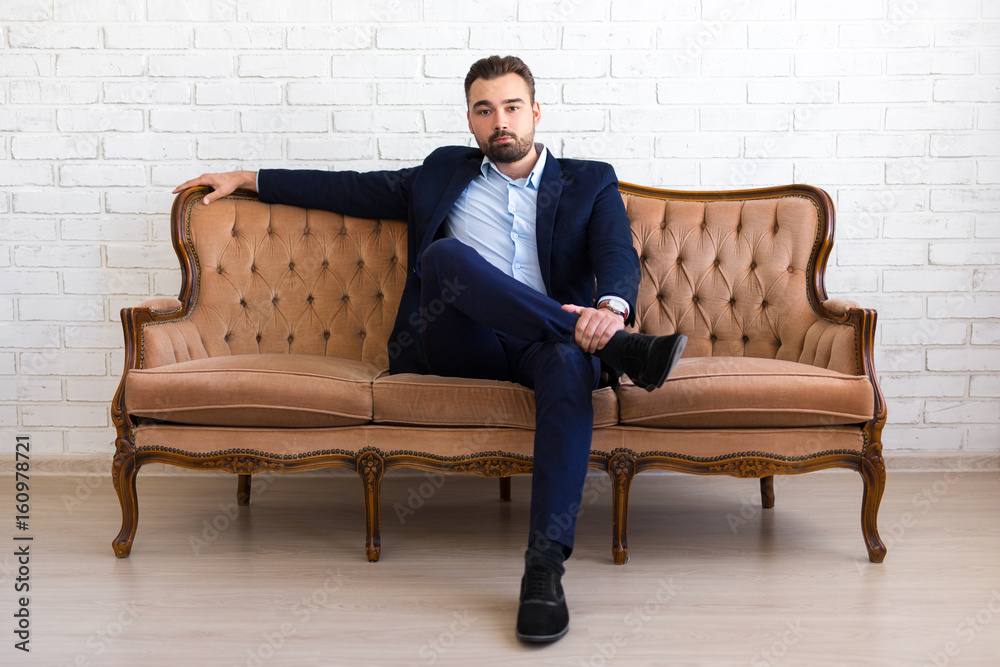 richness and success concept - handsome bearded man in business suit sitting on vintage sofa richness and success concept - handsome bearded man in business suit sitting on vintage sofa