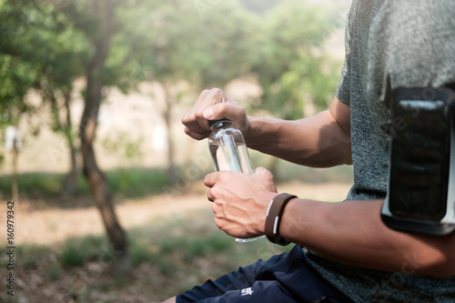 Sport man and pure water. Sport man open water bottle. 