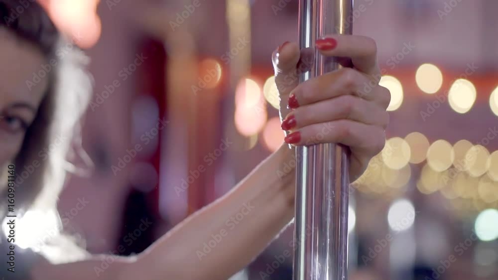 Young girl seductive moves with a pole in the dancing club. Long fingers with bright red manicure. Young girl seductive moves with a pole in the dancing club. Long fingers with bright red manicure.