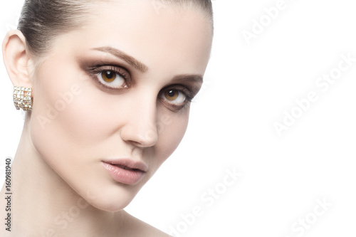 Portrait of young beautiful female with evening makeup looking at camera on white background with copy space