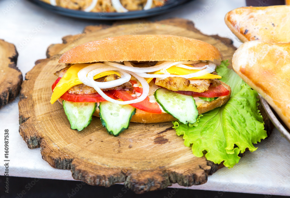 Burger with chicken meat, cheese and fresh vegetables on wooden board. Simple  idea for vegetarian sandwich