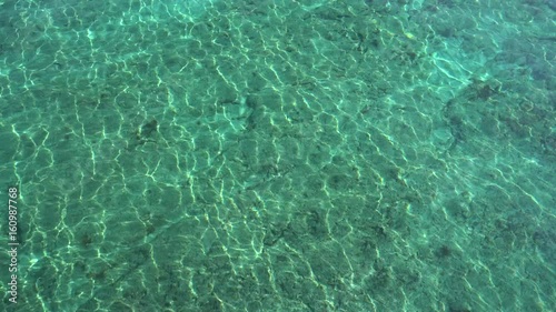 Top view of turquosie sea waves. Seabed with sunlight spots is visible through water photo