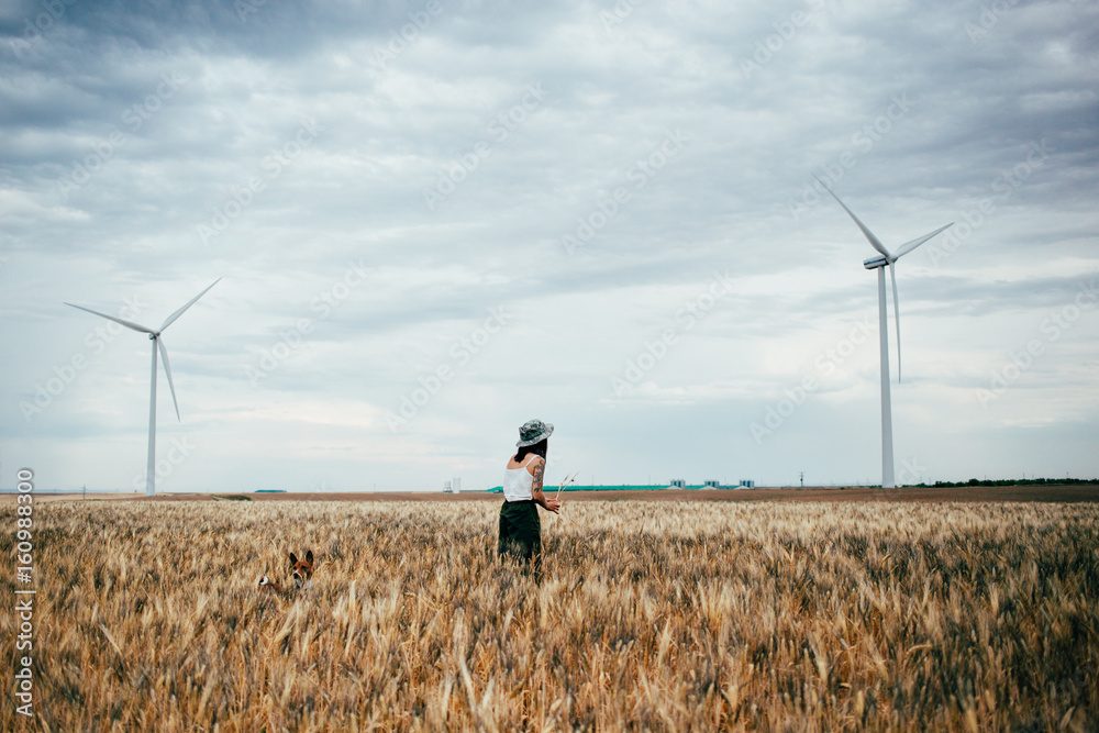 custom made wallpaper toronto digitalYoung petite female explorer picks up field flowers in between wheat fields and renewable energy windmills, lost in nature and tranquility