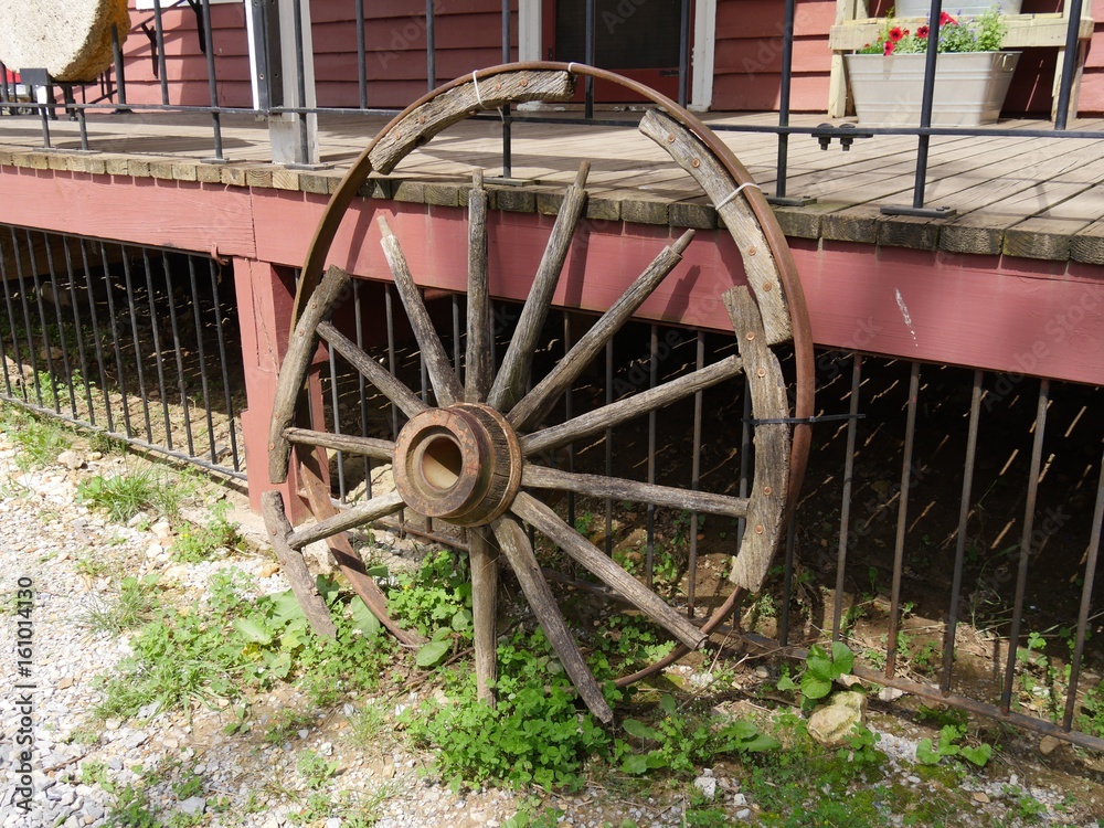 A broken old wagon wheel made of wood and metal on display as a reminder of its useful days