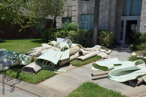 Carpet rolls in front yard of installation with piles of debris