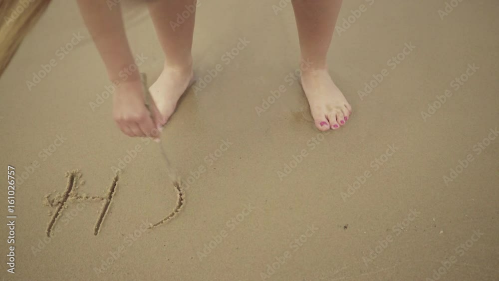 Woman relaxing on beach, standing in water on sea shore, writing word holidays on sand, having fun. Woman relaxing on beach, standing in water on sea shore, writing word holidays on sand, having fun.
