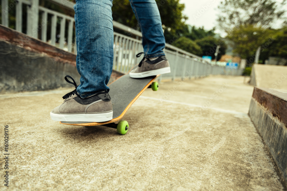 young skateboarder legs riding skateboard at skatepark young skateboarder legs riding skateboard at skatepark