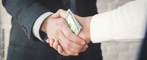 Photos Businessmen making handshake with money in hands