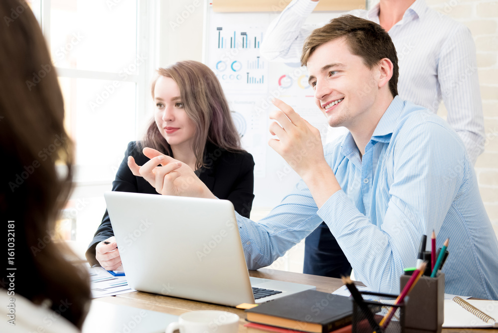 Happy businessman discussing work with his colleagues in the office Happy businessman discussing work with his colleagues in the office