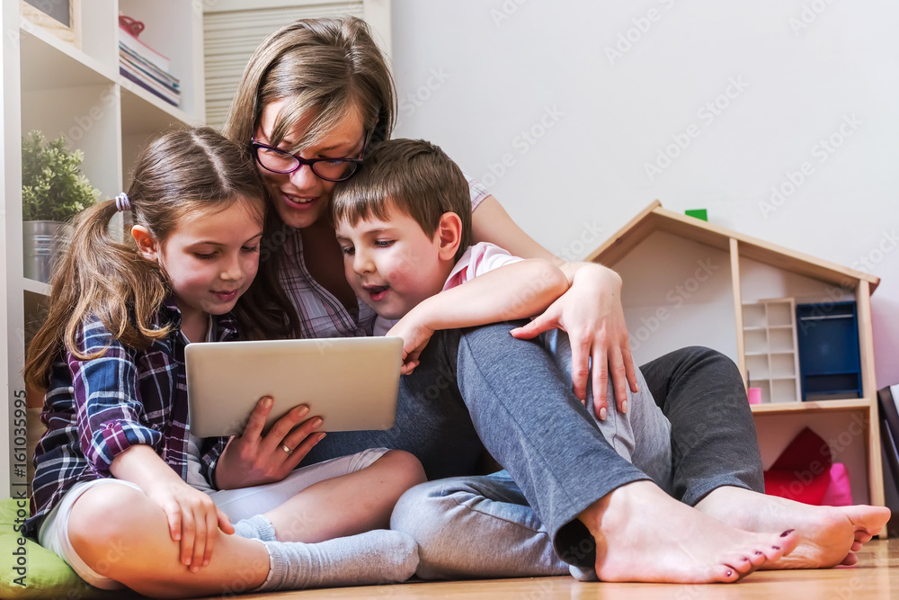 Mother with two children using digital tablet at home Mother with two children using digital tablet at home