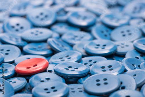 One red button on a heap of blue buttons