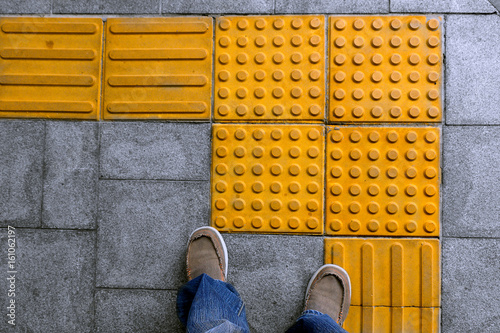 shoes on block tactile paving for blind handicap on tiles pathway, walkway for blindness people. photo