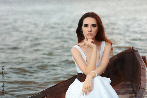 Thoughtful Woman in White Dress Sitting in an Old Boat  © nicoletaionescu