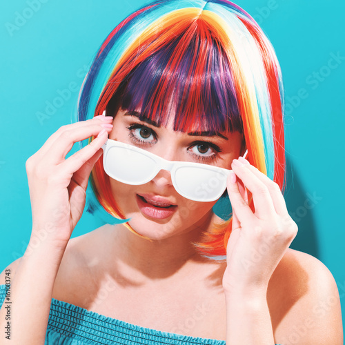 Beautiful woman in a colorful wig on a blue background