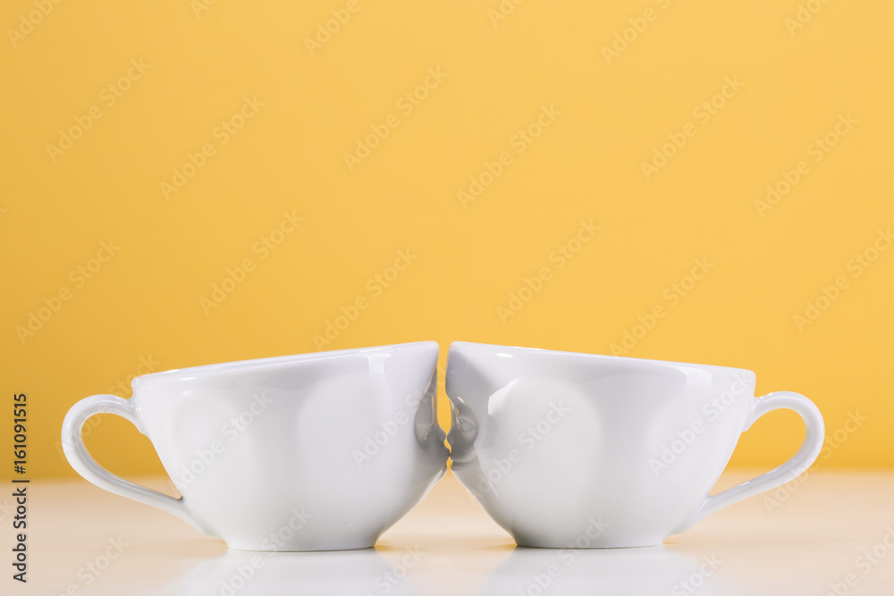 Fototapeta premium Two white cups on a yellow background. I love uou.