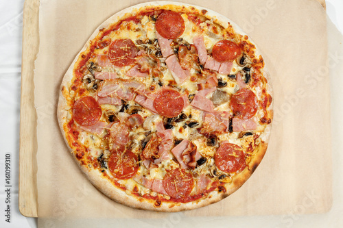 Pizza italian with bacon and salami on a paper.