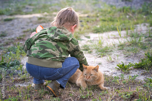 The boy is playing with a red cat. photo