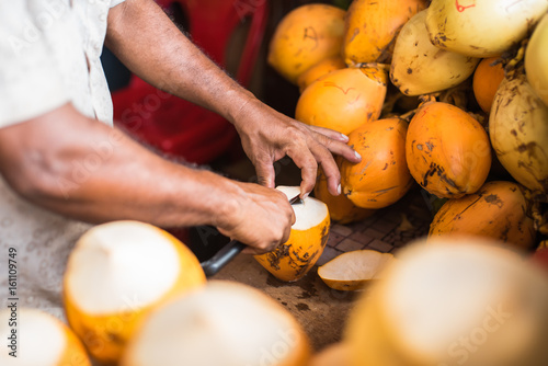 Orange fresh coconut peeling and shelling with heavy chop knife for juice in Male,Maldives photo