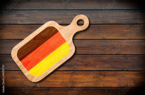 Concept of German cuisine. Cutting board with a German flag on a wooden background