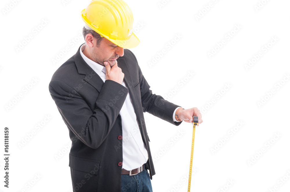 Architect wearing hardhat holding measuring tape and thinking Architect wearing hardhat holding measuring tape and thinking