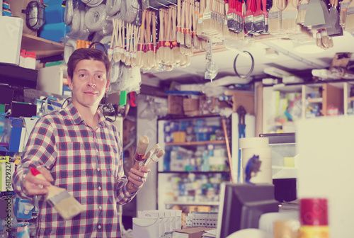 Worker is standing near the counter and selling brushes