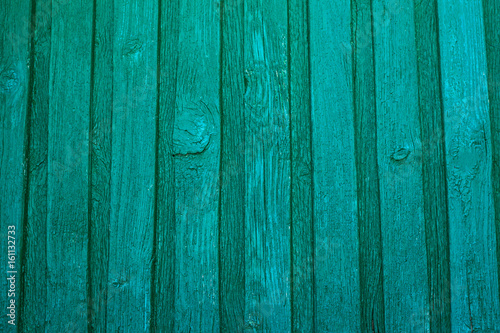 Vintage wooden texture of an old fence painted green. Vertical texture on background